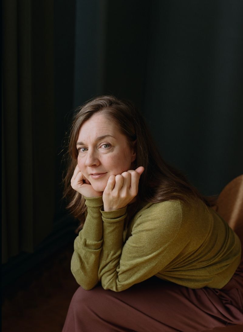 Woman in light in front of window and blue wall