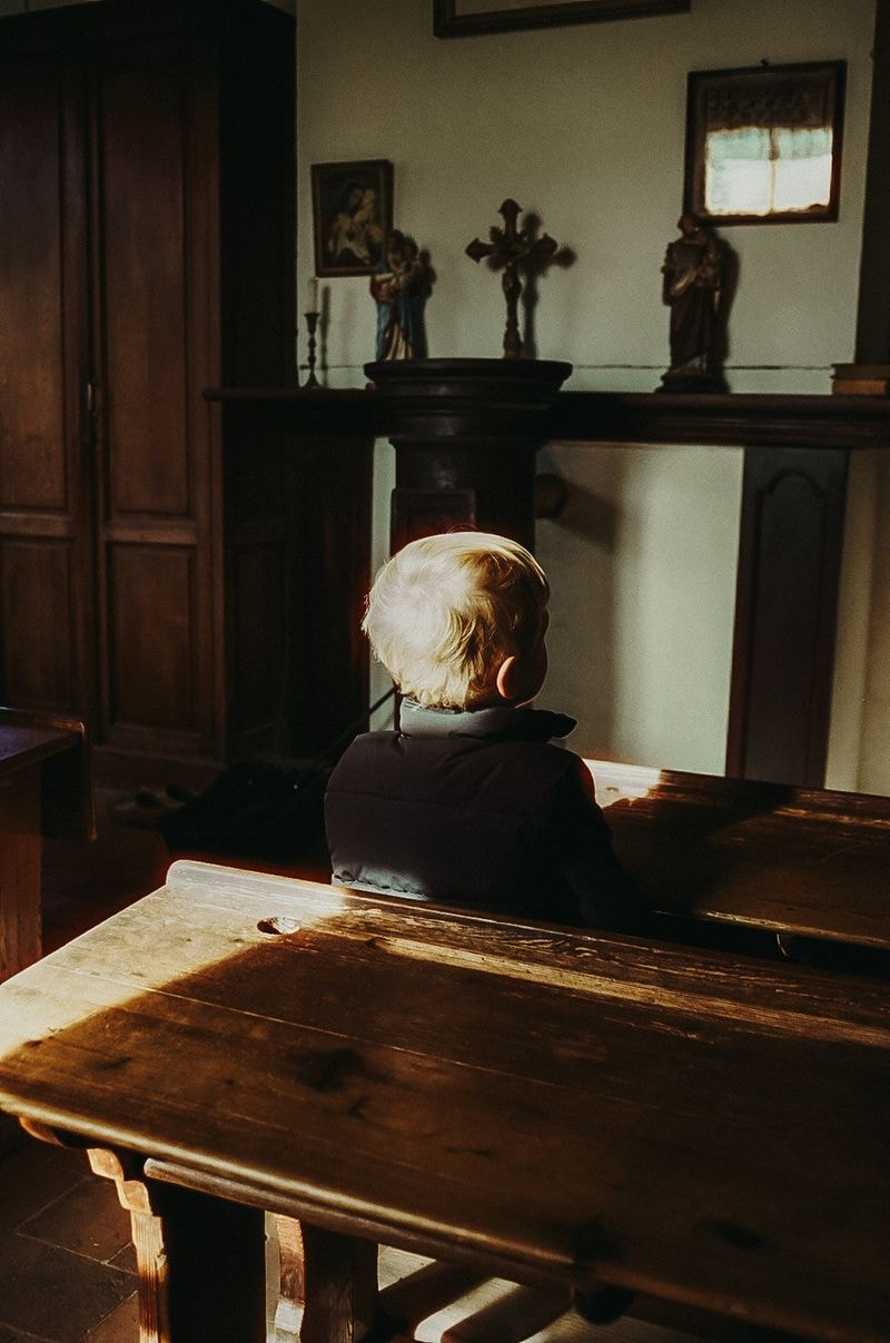 Blond jongetje van achteren zittend in schoolbankje in België